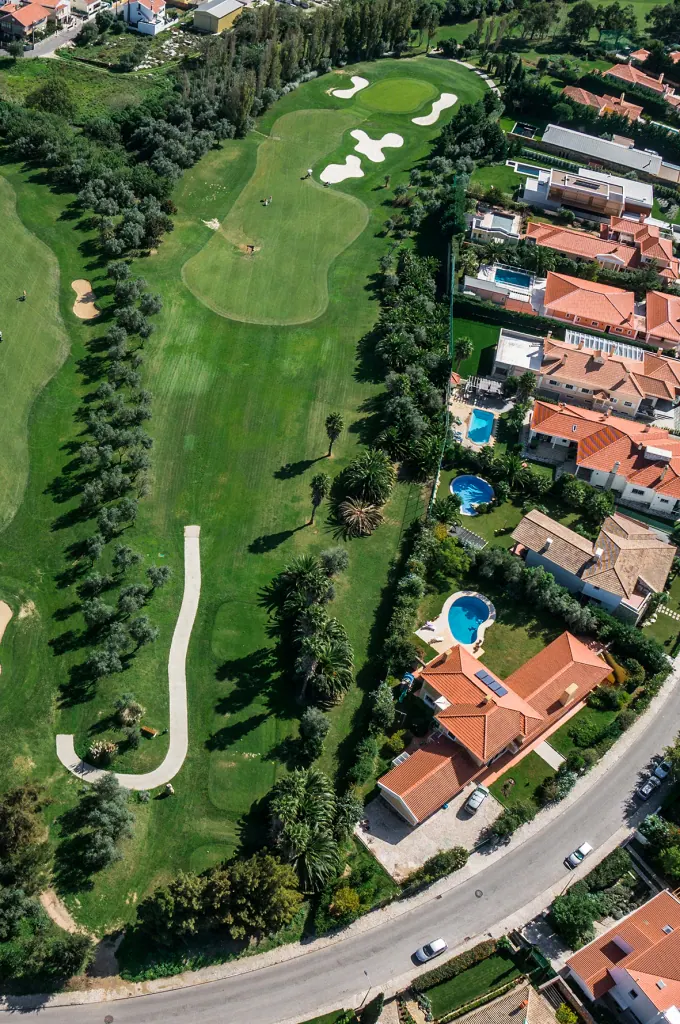 Aerial view of Beloura: homes with gardens and pools alongside a golf fairway
