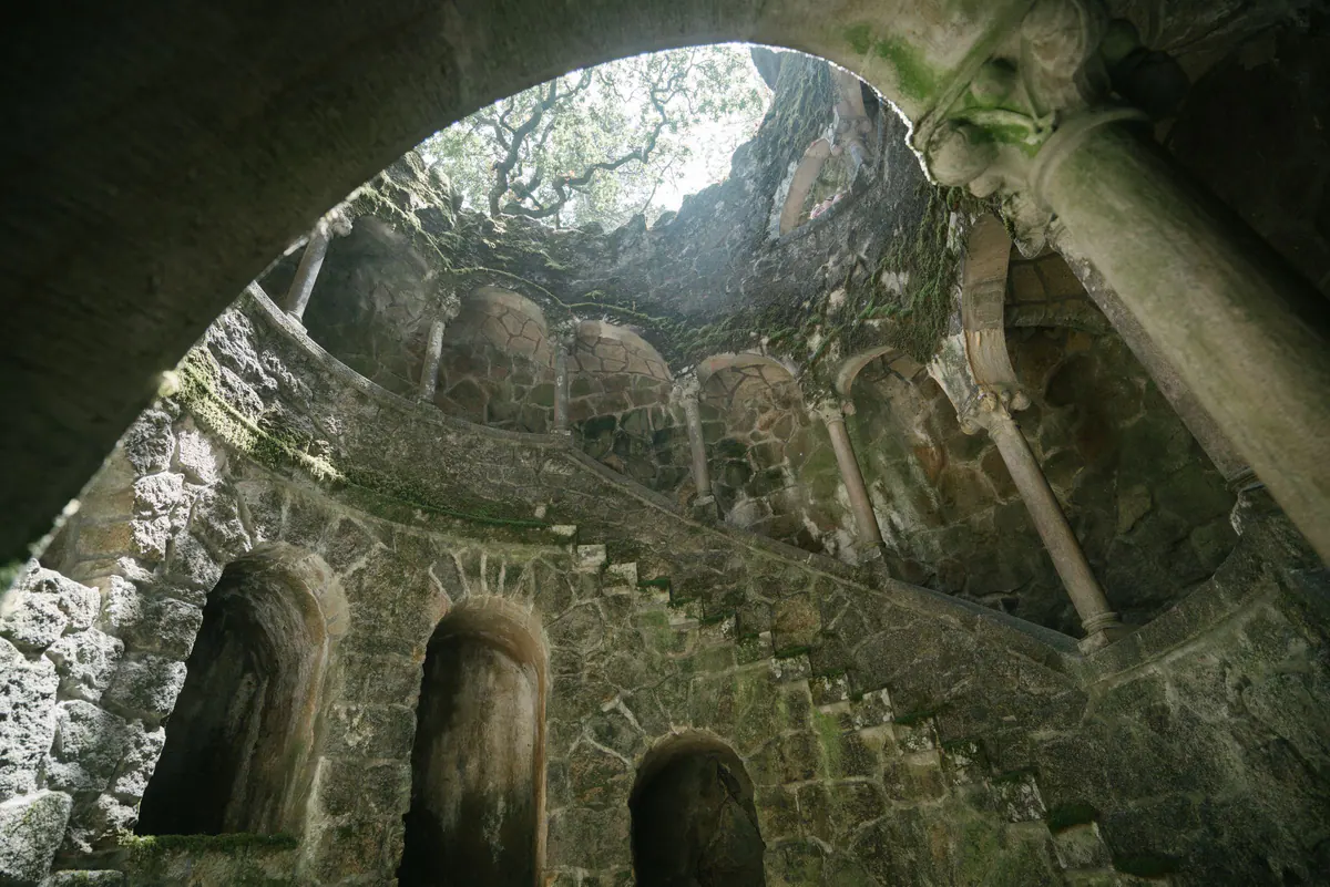 Inside the Initiation Well at Quinta da Regaleira: mossy spiral stone galleries